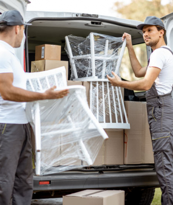 Delivery company employees unloading cargo van vehicle, delivering some goods and furniture to a clients home. Relocation and professional delivery concept