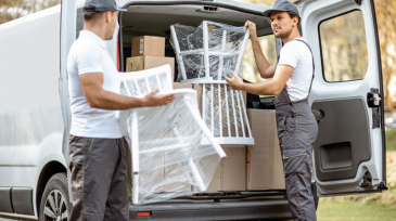 Delivery company employees unloading cargo van vehicle, delivering some goods and furniture to a clients home. Relocation and professional delivery concept